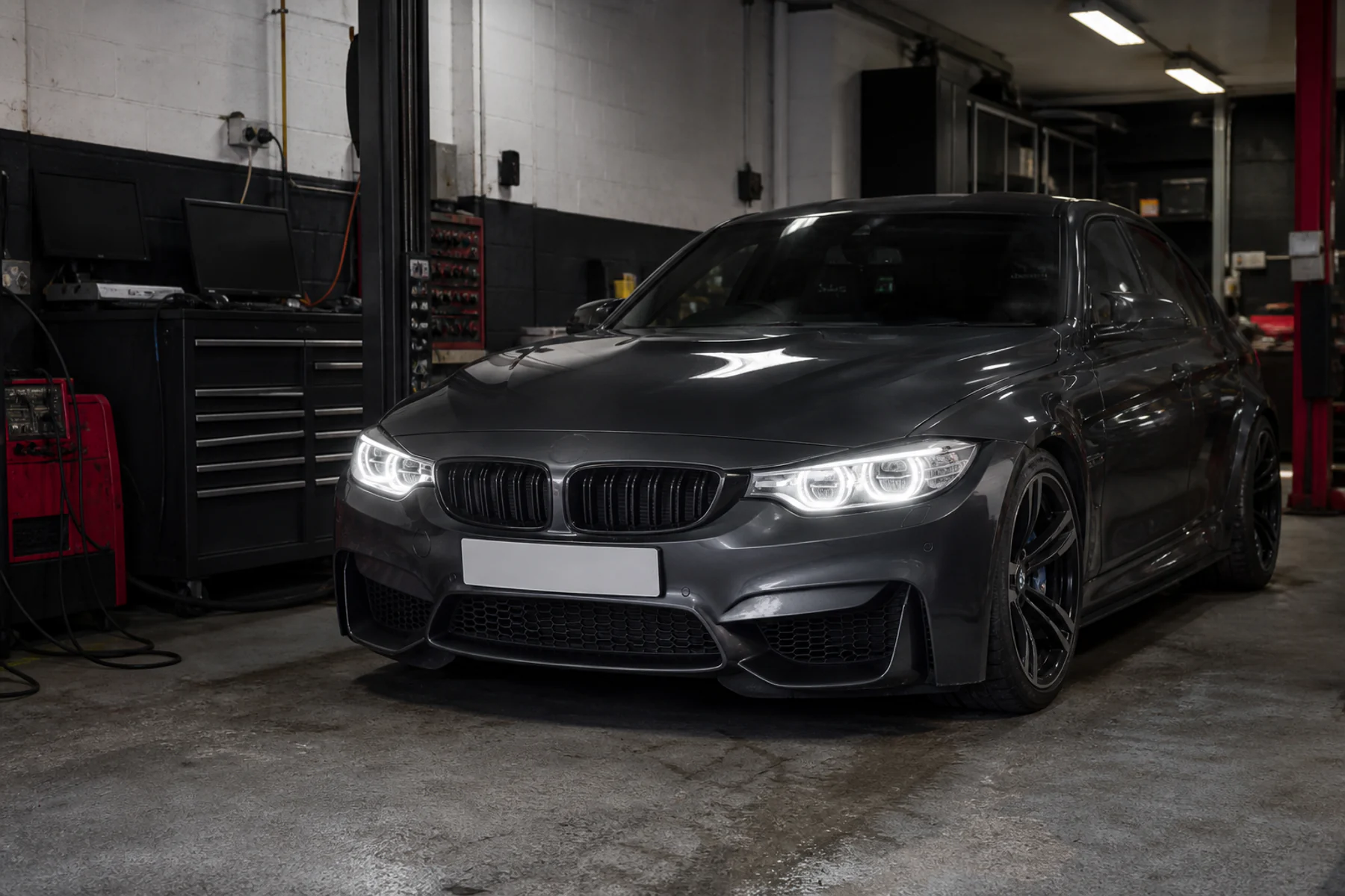 Dark Audi RS3 lit by its LED headlights inside the Navs HID Direct workshop in Bradford